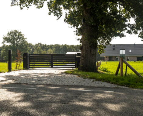 Elektrische draaipoort met houtlook horizontale planken in een landelijke omgeving draaipoort oprit